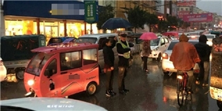 Ấm lòng người phụ nữ che dù cho viên cảnh sát dưới trời mưa 